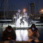 Dos personas junto a un Belén luminoso el día de la inauguración del encendido de luces de la segunda edición de 'Nadal al Port', en el Puerto de Barcelona, Catalunya (España)