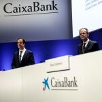 El presidente de CaixaBank, Jordi Gual (d) y el consejero delegado, Gonzalo Gortázar (i), durante la junta de accionistas para dar luz verde a la fusión con Bankia