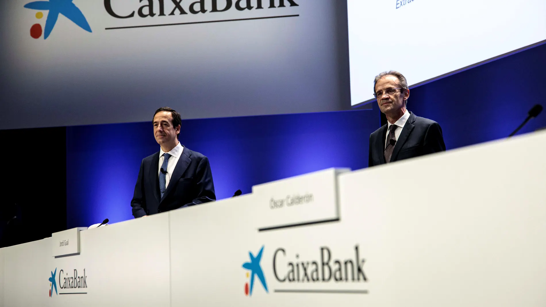 El presidente de CaixaBank, Jordi Gual (d) y el consejero delegado, Gonzalo Gortázar (i), durante la junta de accionistas para dar luz verde a la fusión con Bankia