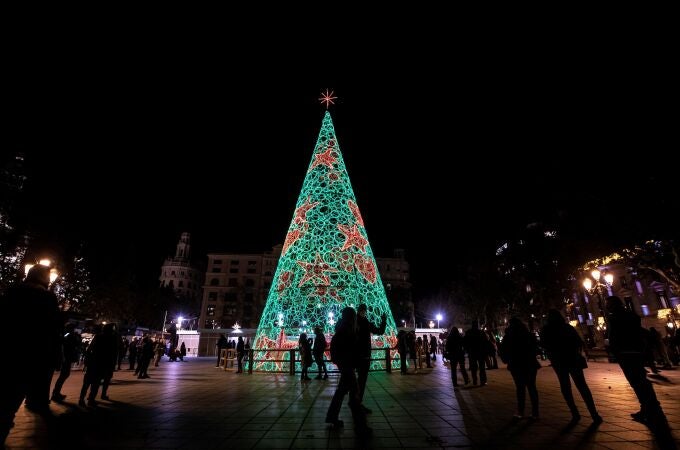 Varias personas pasean frente al árbol de navidad iluminado tras el acto de encendido de luces del ayuntamiento de València. EFE/Biel Aliño