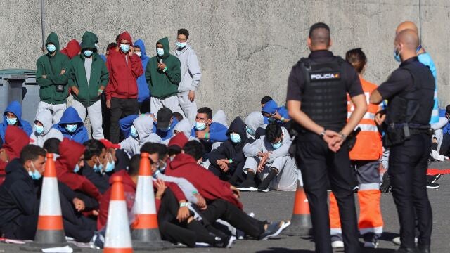 Varios inmigrantes descansan en el muelle de Arguineguín tras ser rescatados por Salvamento Marítimo en Gran Canaria el pasado diciembre