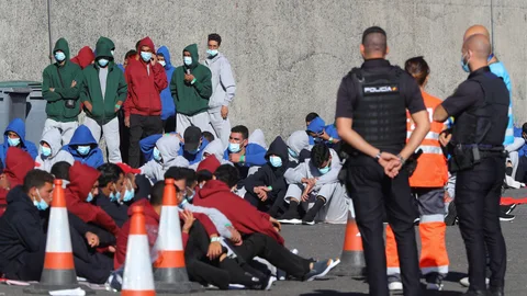 Varios inmigrantes descansan en el muelle de Arguineguín tras ser rescatados por Salvamento Marítimo en Gran Canaria el pasado diciembre
