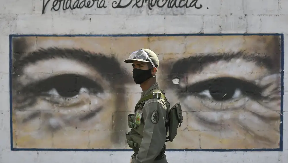 Un soldado frente a un mural del fallecido presidente Hugo Chávez en un colegio electoral