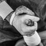Un médico sostiene la mano de un paciente ingresado en la UCI