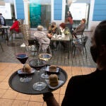 Una camarera se dispone a servir en una terraza de un restaurante de Avilés, Asturias (España)