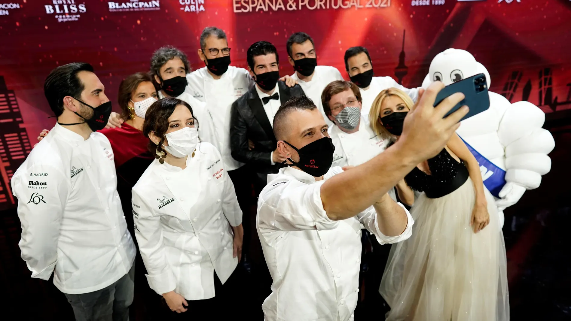 El chef David Muñoz (c); la presidenta de la Comunidad de Madrid, Isabel Díaz Ayuso (2i); el alcalde de Madrid, José Luis Martínez Almeida (3d); y los presentadores de la gala, los actores Cayetana Guillén Cuervo (d), y Miguel Ángel Muñoz (5d), entre otros, durante la gala de la Guía Michelin España y Portugal 2021 que se ha celebrado este lunes en la Real Casa de Correos y por primera vez se ha realizado de forma digital para adecuarse a las medidas sanitarias para evitar el coronavirus.