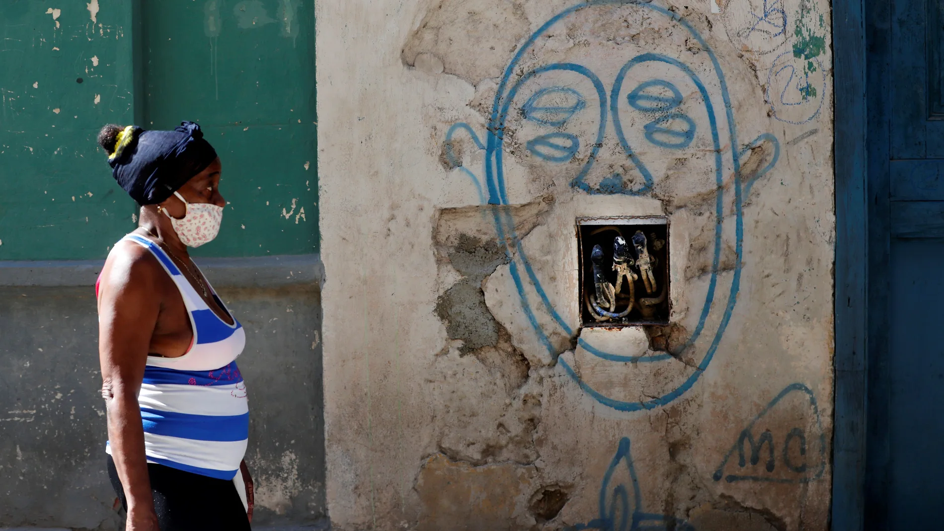 Una mujer camina frente a una pared con cables eléctricos expuestos en La Habana (Cuba)