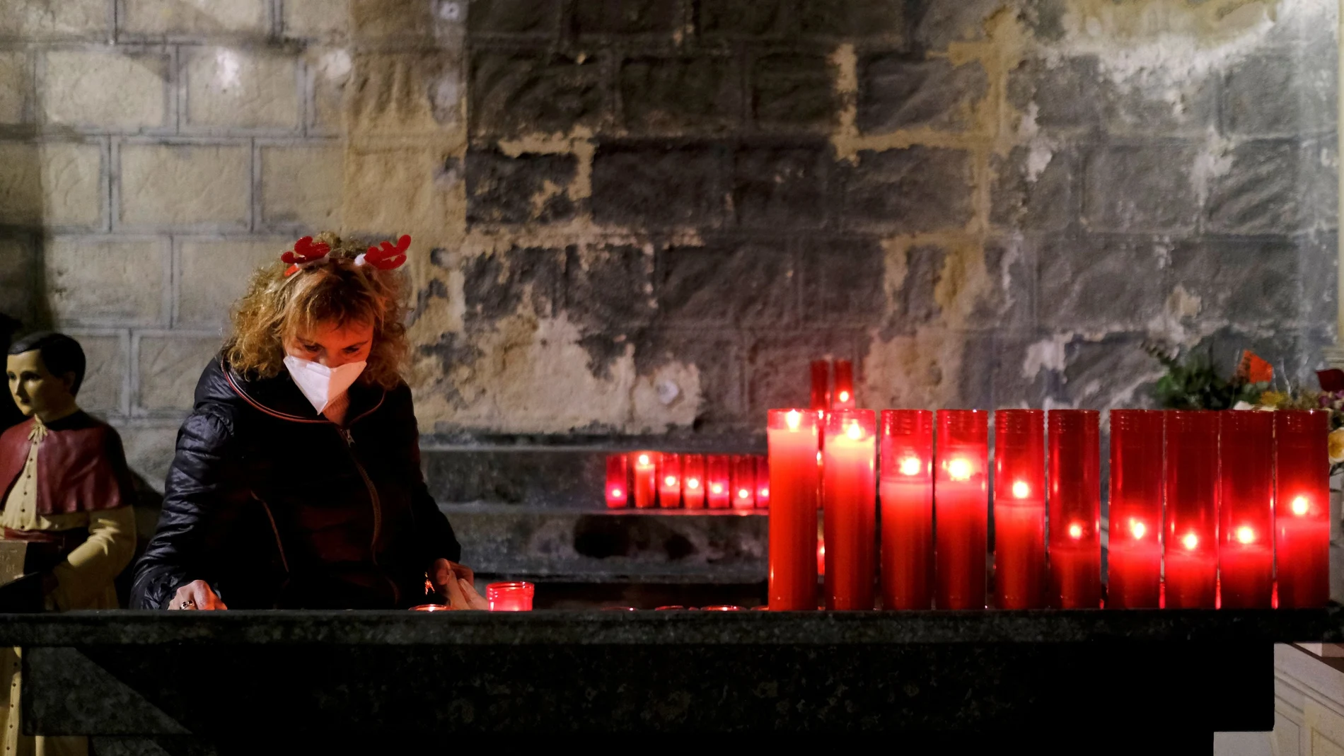 Un mujer enciende una vela en la iglesia de Sant Jaume de Barcelona. REUTERS/Nacho Doce