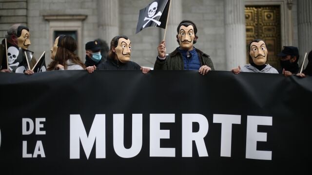 Manifestantes con máscaras de Dalí se concentran con pancartas con el símbolo de la muerte frente al Congreso de los Diputados contra la eutanasia