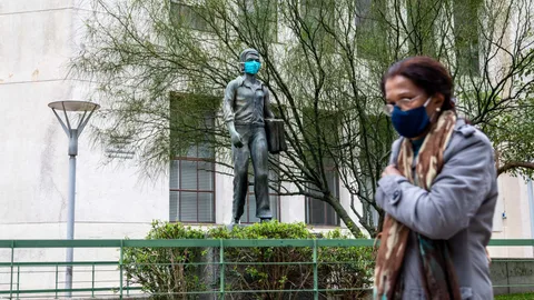 Una mujer pasa frente a una estatua con mascarilla en Montevideo, acción promovida por el Gobierno para fomentar el uso de mascarilla. (Foto de ARCHIVO)07/05/2020