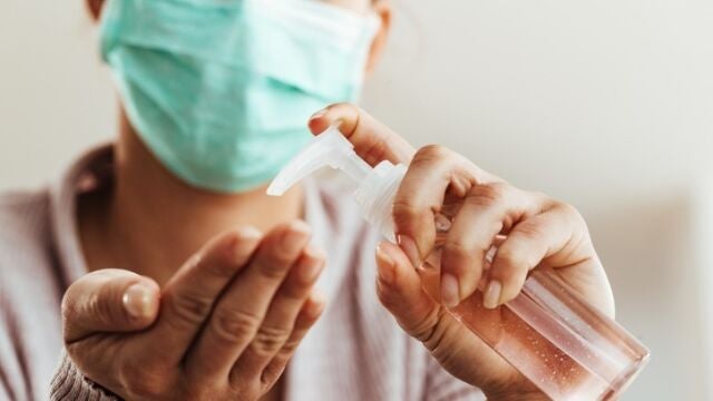Mujer con mascarilla y gel hidroalcohólico.