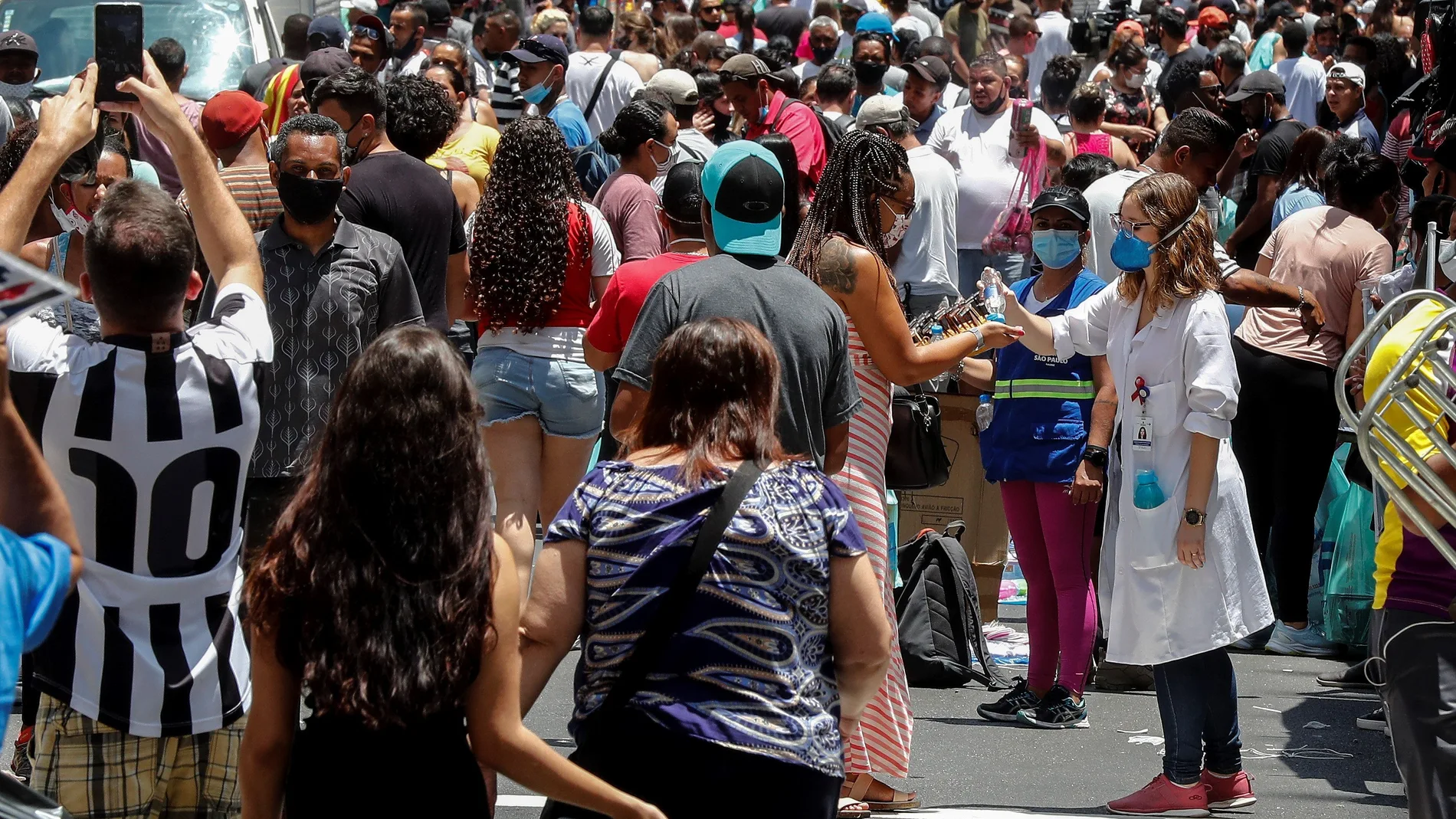 AME5799. SAO PAULO (BRASIL), 18/12/2020.- Una enfermera desinfecta las manos de las personas que caminan en una concurrida vía comercial hoy, en el centro de Sao Paulo (Brasil). El Gobierno brasileño exigirá a partir del 30 de diciembre próximo que los ciudadanos nacionales y extranjeros que desembarquen en cualquier aeropuerto del país procedentes del exterior presenten un examen demostrando que no están contagiados de covid-19. Brasil registró el jueves 1.092 muertes por covid, con lo que volvió a superar el millar de fallecimientos diarios por primera vez desde el 30 de septiembre (1.031) y acumula 184.827 víctimas de la pandemia. EFE/ Sebastiao Moreira