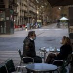 Una pareja toma un café en un local de Las Ramblas de Barcelona, tradicionalmente abarrotadas de gente y ahora desérticas