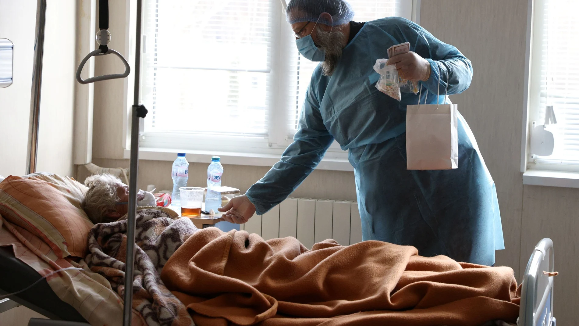 Un sacerdote ortodoxo regala un icono a un paciente de covid ingresado en el Hospital Santa Ana de Sofía, en Bulgaria