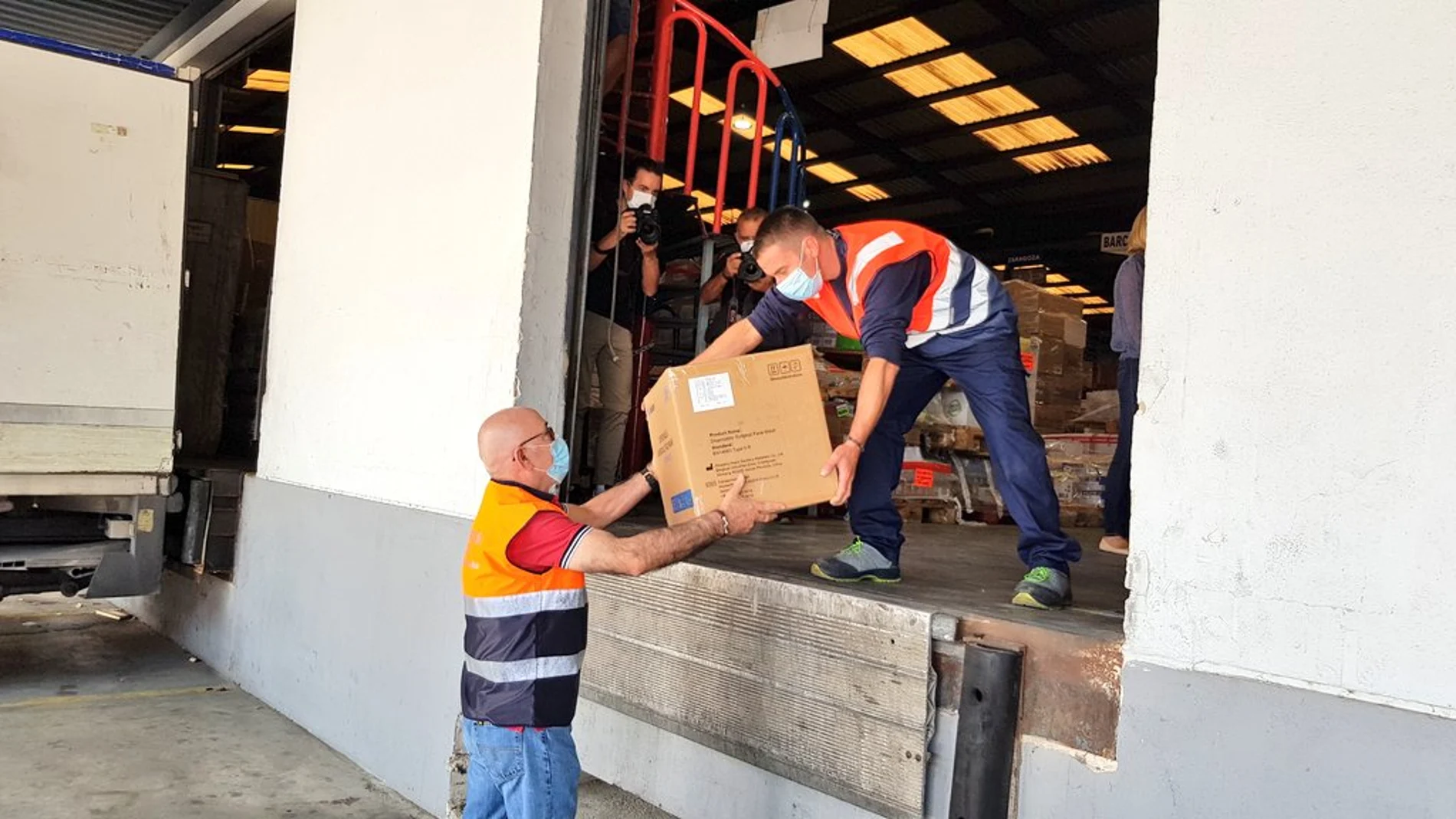 Operarios descargan las cajas con las mascarillas para su reparto