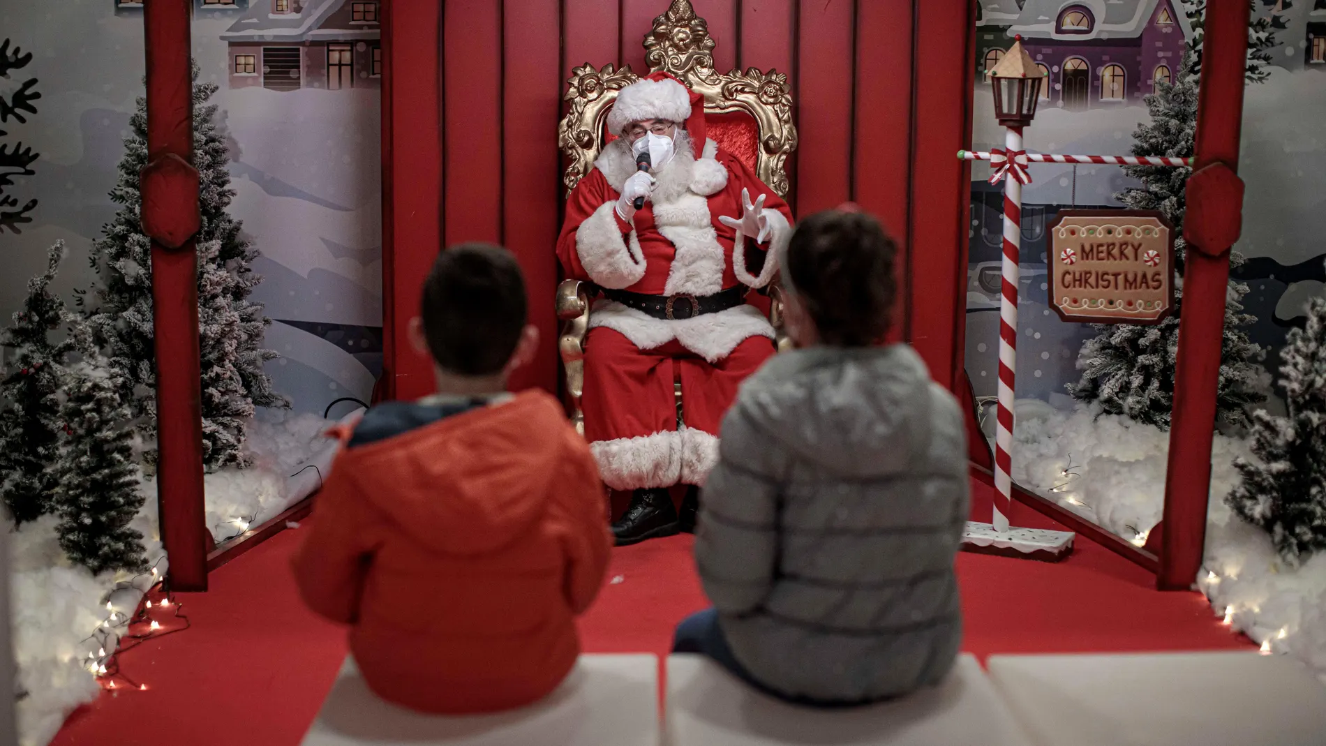 GRAFCVA667. VALENCIA, 24/12/2020.- Una persona vestida de Papá Noel con mascarilla conversa con unos niños, manteniendo la distancia de seguridad para evitar contagios de coronavirus, esta mañana en un centro comercial de València. EFE/Biel Aliño