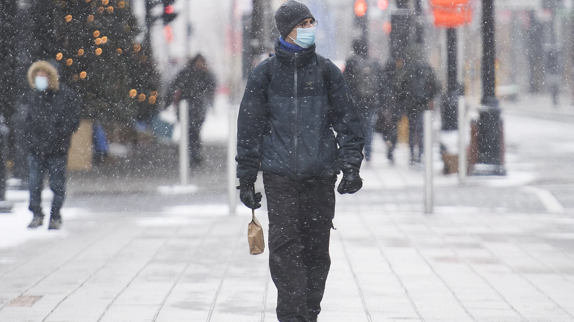 A man wears a face mask as he walks along Sainte-Catherine Street on Boxing Day in Montreal, Saturday, Dec. 26, 2020, as the COVID-19 pandemic continues in Canada and around the world. (Graham Hughes/The Canadian Press via AP)