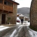 Un hombre pasea con su perro por una calle de la localidad de Orzonága (León) cubierta por la nieve caída