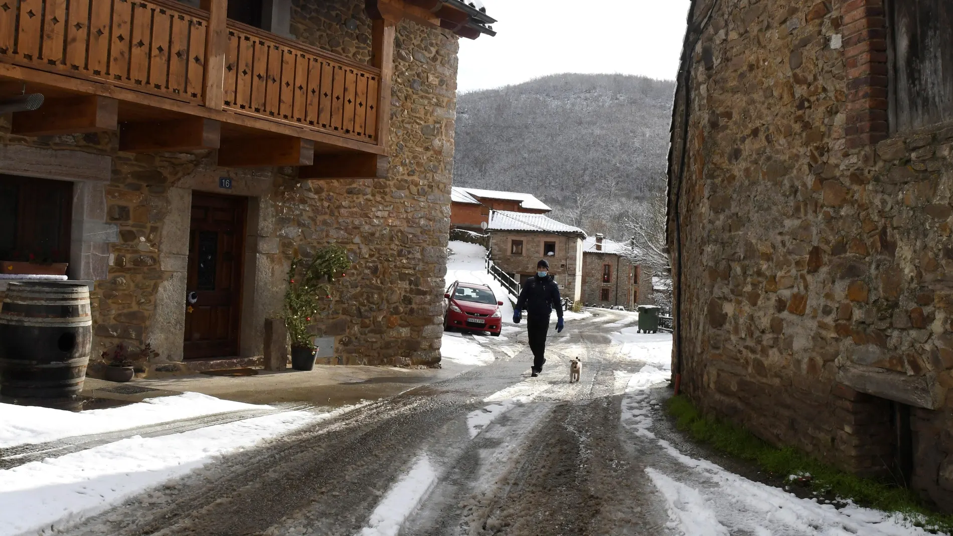Un hombre pasea con su perro por una calle de la localidad de Orzonága (León) cubierta por la nieve caída