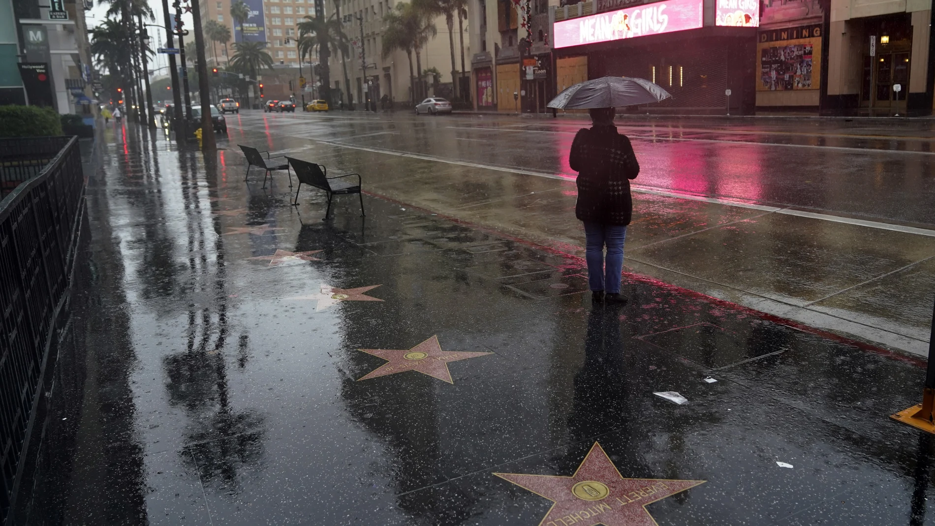 A woman waits at a bus stop in the rain Monday, Dec. 28, 2020, in the Hollywood section of Los Angeles. Rain, hail and snow fell Monday as Southern California saw its first significant storm of the season. (AP Photo/Marcio Jose Sanchez)