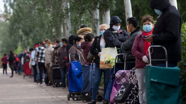 Filas de personas sin recursos económicos hacen cola para que la Asociación de Vecinos de Aluche, sita en la calle Quero, les proporcione productos alimenticios