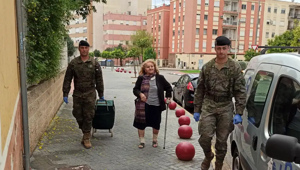 Dos militares ayudan a una mujer a llevar la compra en Alzira (Valencia)
