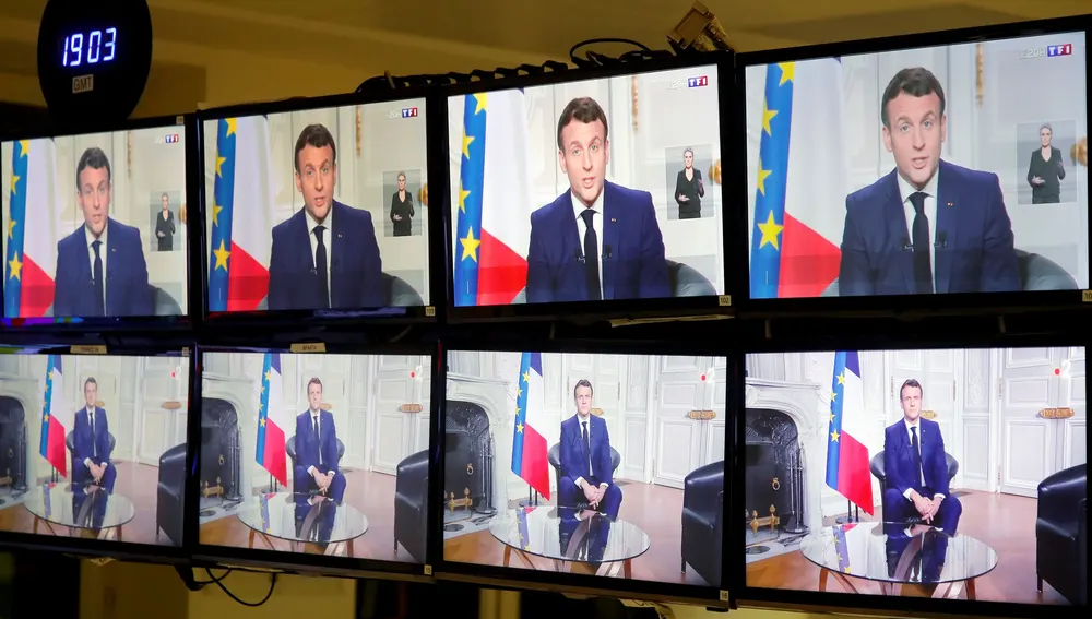 El presidente francés Emmanuel Macron en las pantallas mientras ofrece el tradicional discurso de Año Nuevo
