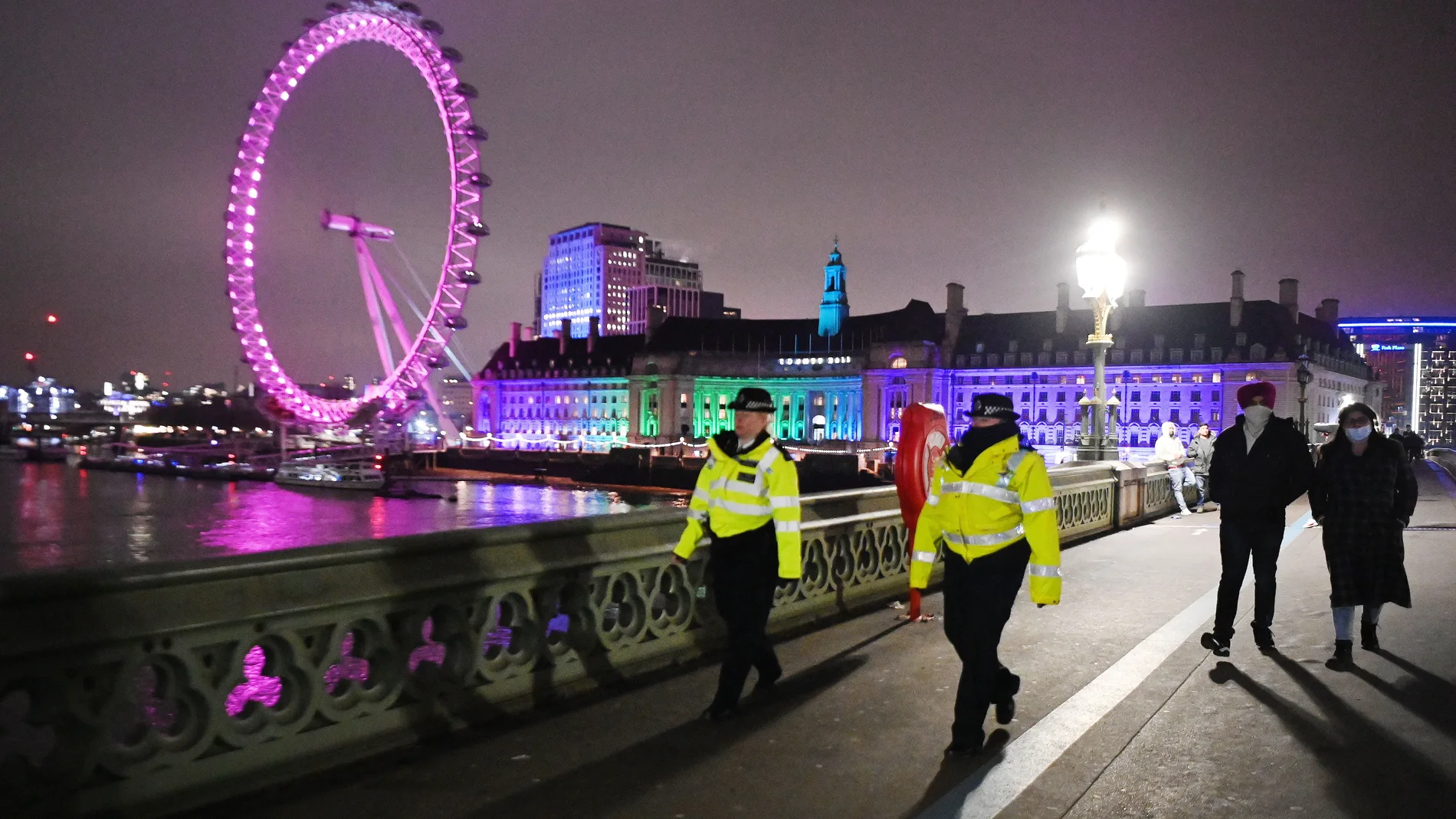 London (United Kingdom), 31/12/2020.- Police officers walk along Westminster Bridge in front of the London Eye, in London, Britain, 31 December 2020. New Year's Eve celebrations are not taking place in London due to coronavirus restrictions. The UK government is encouraging people to stay home as Covid-19 cases continue to surge. (Reino Unido, Londres) EFE/EPA/ANDY RAIN