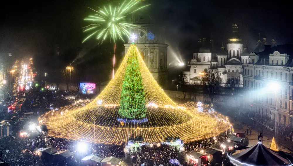 Crowds of people celebrate the New Year around the Christmas tree with the St. Sofia Cathedral in the background in Kyiv, Ukraine, Friday, Jan. 1, 2021. Despite of COVID-19 quarantine restrictions, a lot of Ukrainians enjoy outdoor New Year events, often ignoring protective measures. (AP Photo/Efrem Lukatsky)