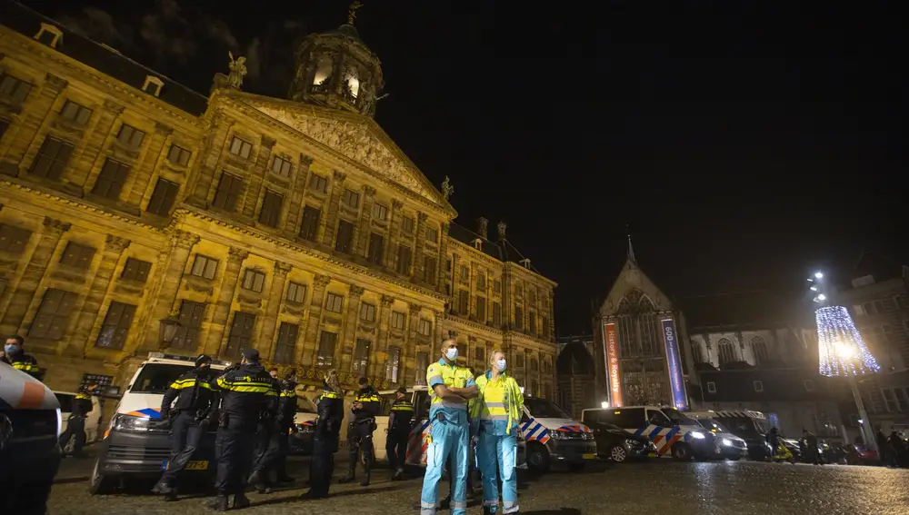 Police and ambulance personnel line up in front of the Royal Palace on Dam Square just before midnight in Amsterdam, Netherlands, Thursday, Dec. 31, 2020. As the world says goodbye to 2020, a year ruined by the coronavirus, there will be countdowns and live performances, but no massed jubilant crowds in traditional gathering spots like the Champs Elysees in Paris and New York City's Times Square this New Year's Eve. (AP Photo/Peter Dejong)