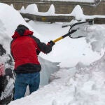 Un hombre retira la gran cantidad de nieve acumulada en su vehículo estacionado en el Puerto de Pajares de León