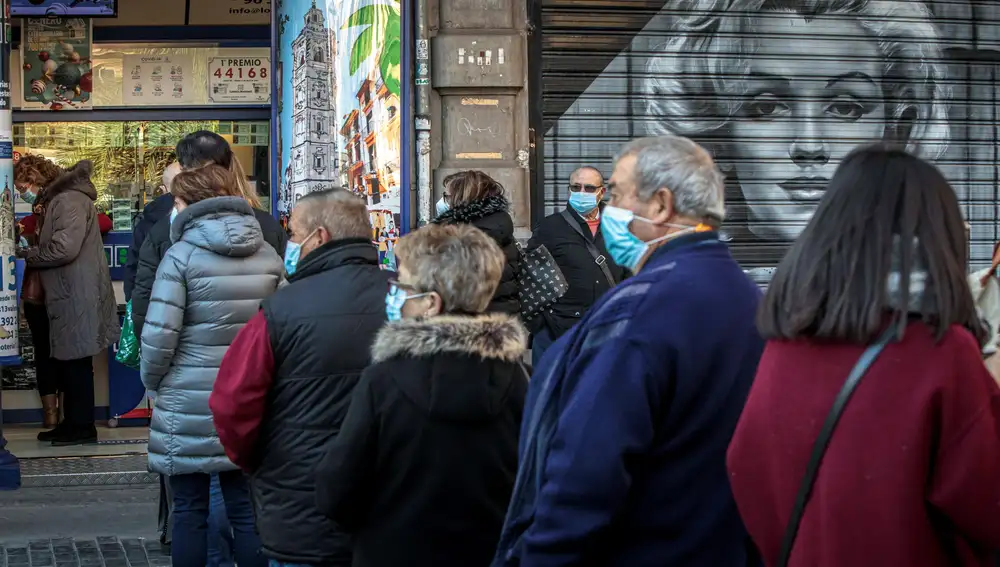 GRAFCVA788. VALENCIA, 04/01/2021.- Varias personas hacen cola frente a una administración de lotería en València, a falta de dos días para la celebración del sorteo de El Niño. EFE/Biel Aliño