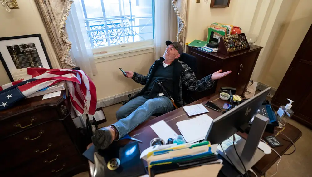 Un partidario del Presidente de los Estados Unidos Donald J. Trump se sienta en el escritorio de la Presidenta de la Cámara de Representantes de los Estados Unidos Nancy Pelosi EFE/EPA/JIM LO SCALZO