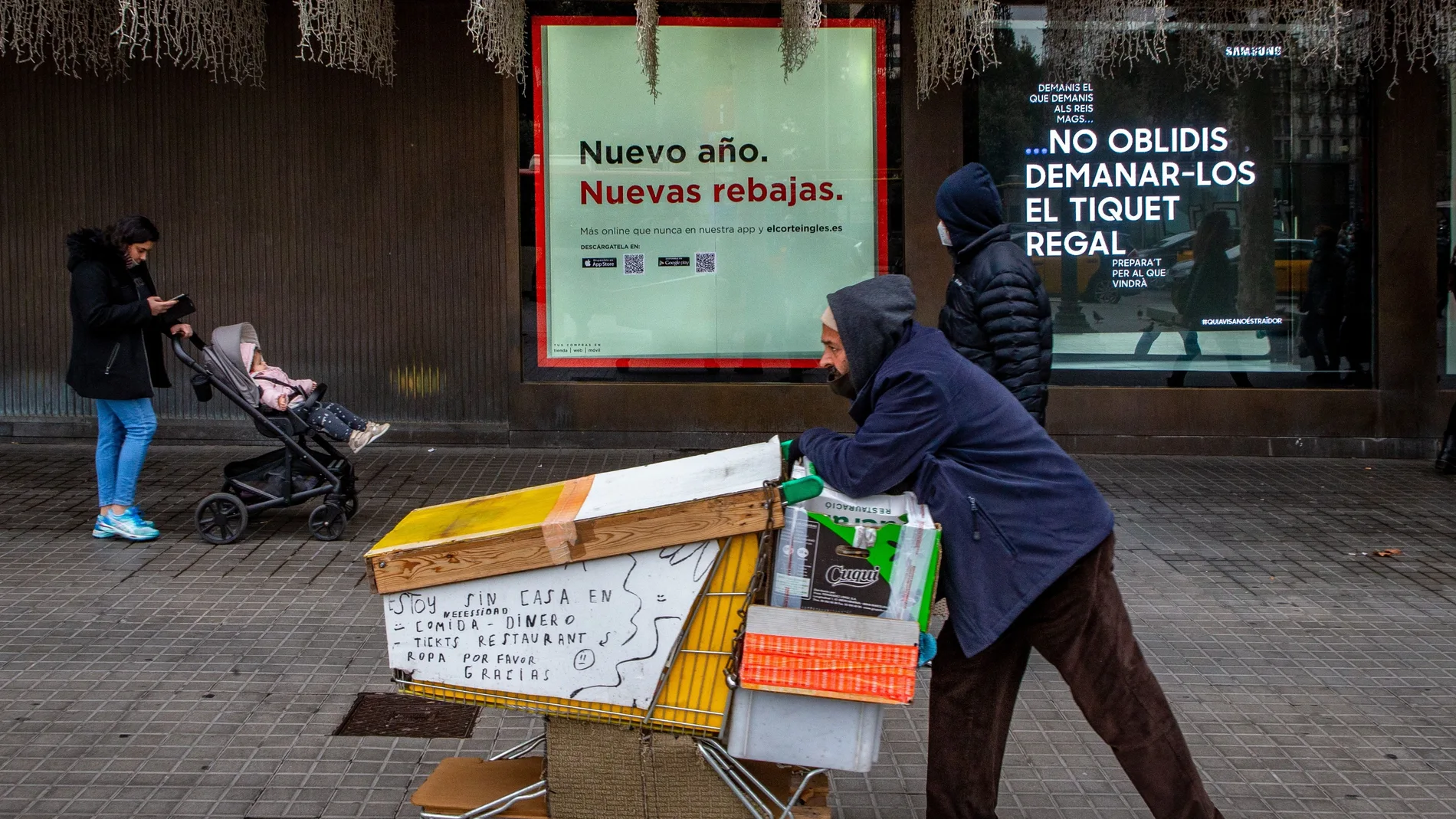 Un señor empuja un carro ante un comercio del centro de Barcelona, este jueves en que en Cataluña arrancan las rebajas de enero el mismo día que entran en vigor las nuevas restricciones de la Generalitat, que han llevado a cerrar los centros comerciales. EFE/ Enric Fontcuberta