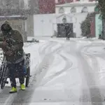 Un hombre con una bicicleta entre la nieve en la Cañada Real, Madrid