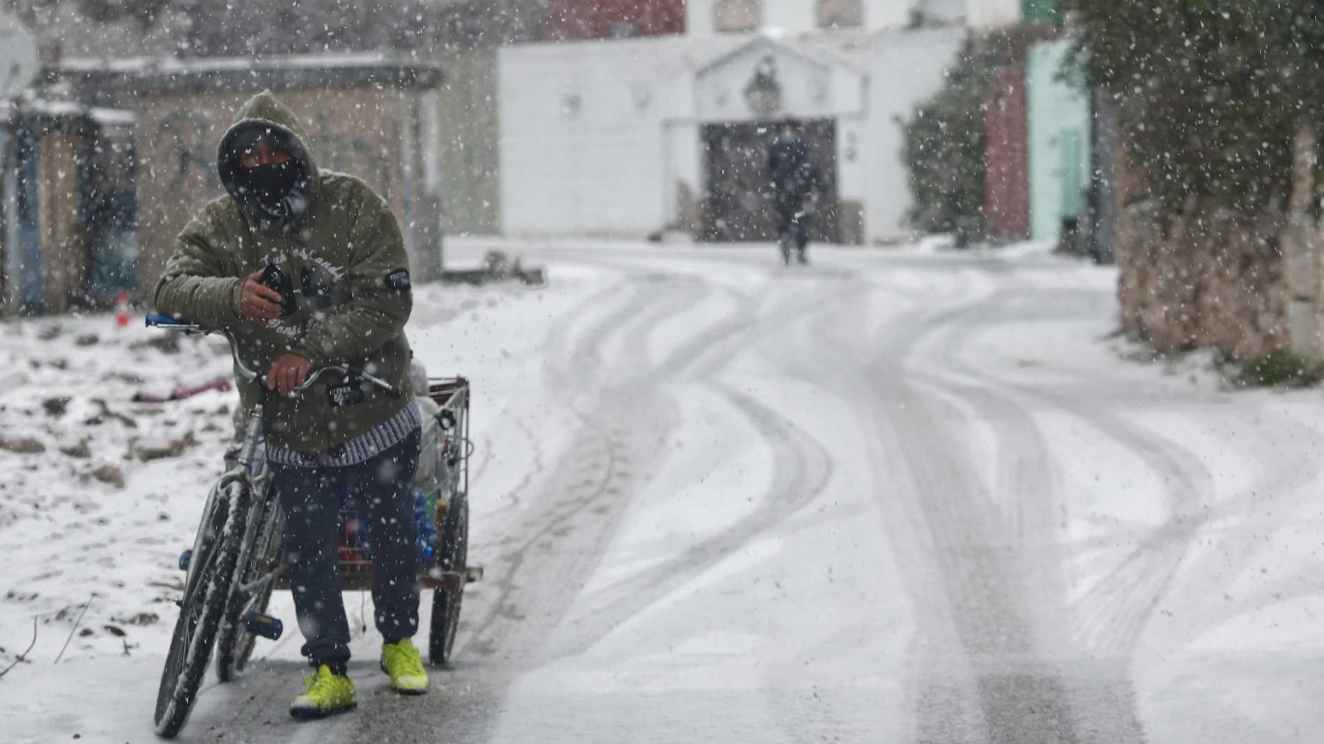 Un hombre con una bicicleta entre la nieve en la Cañada Real, Madrid