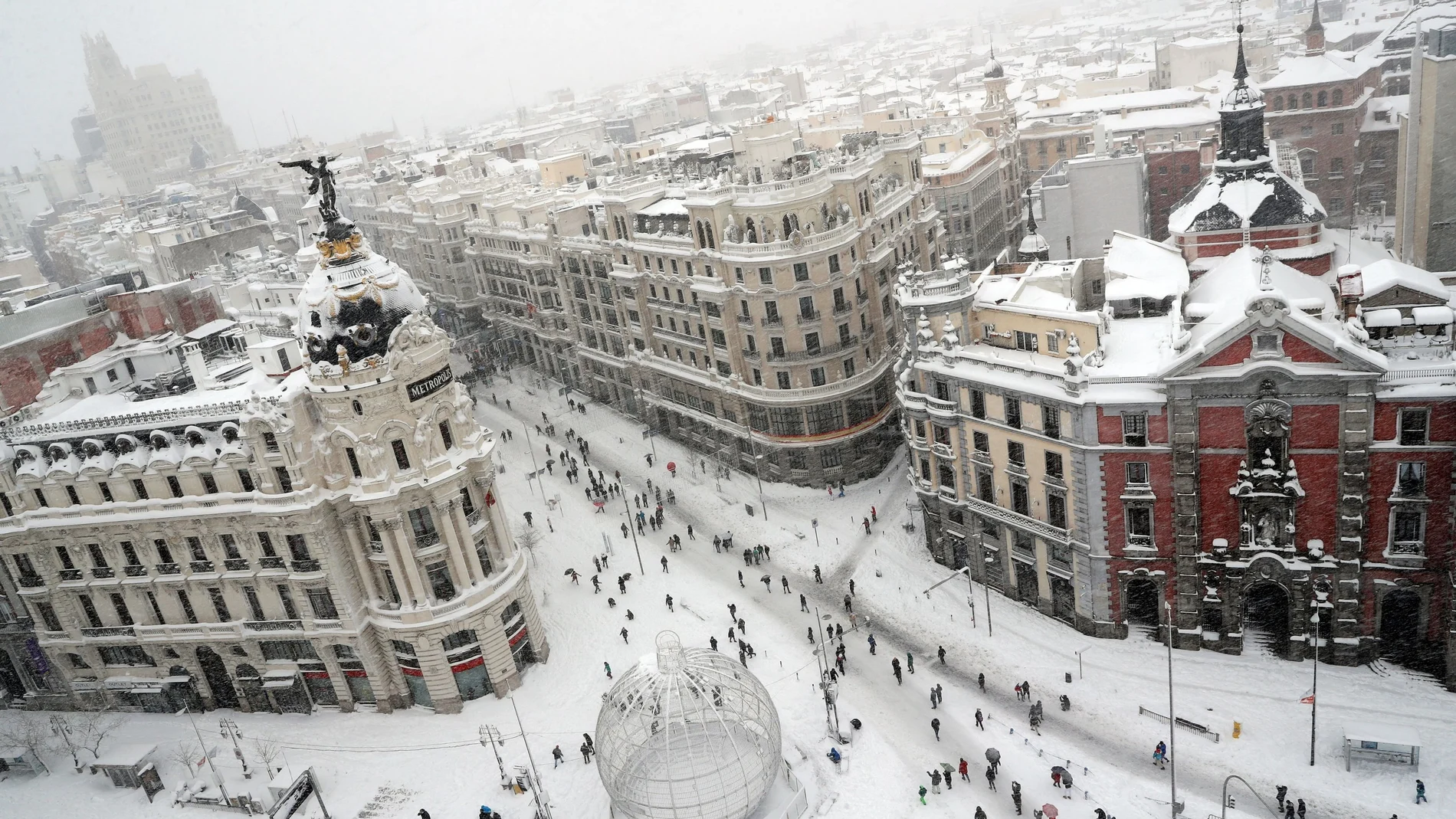 El emblemático cruce madrileño de la Gran Vía con la calle Alcalá ayer cambió el caos de tráfico por ciudadanos paseando sobre la nieve