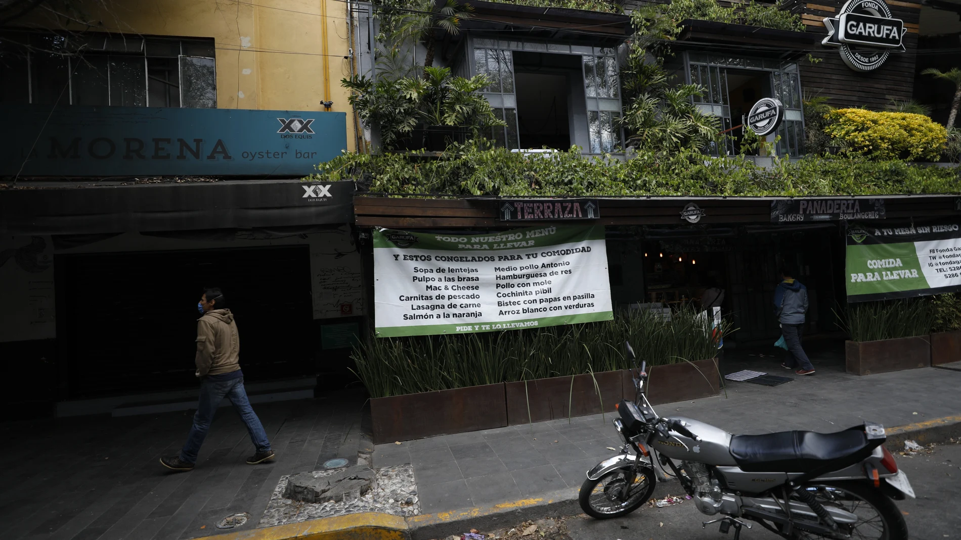 Signs advertise takeout service at a restaurant situated next to two others that have closed permanently amid the COVID-19 pandemic, in Mexico City, Sunday, Jan. 10, 2021. Worried about their ability to survive, many restaurants in the capital and adjacent Mexico State are banning together in a campaign dubbed "Abrir o Morir," Spanish for "Open or Die," and plan to open their doors to diners again on Monday in defiance of ordinances limiting restaurants to take-out service while the Mexico Valley remains under red alert with hospitals nearing full capacity. (AP Photo/Rebecca Blackwell)