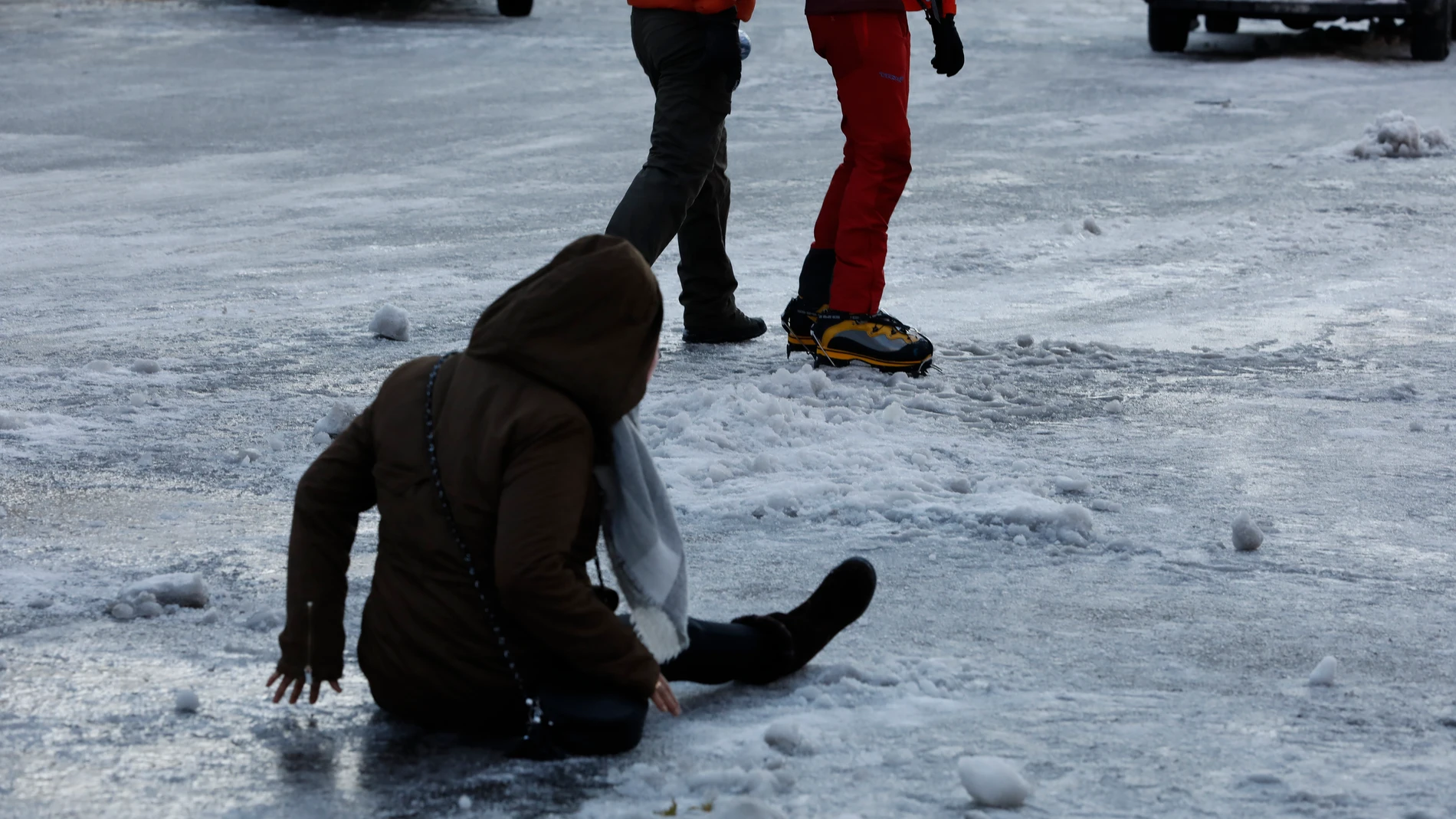 Una mujer cae en el suelo después de resbalar con el hielo ayer en Madrid.