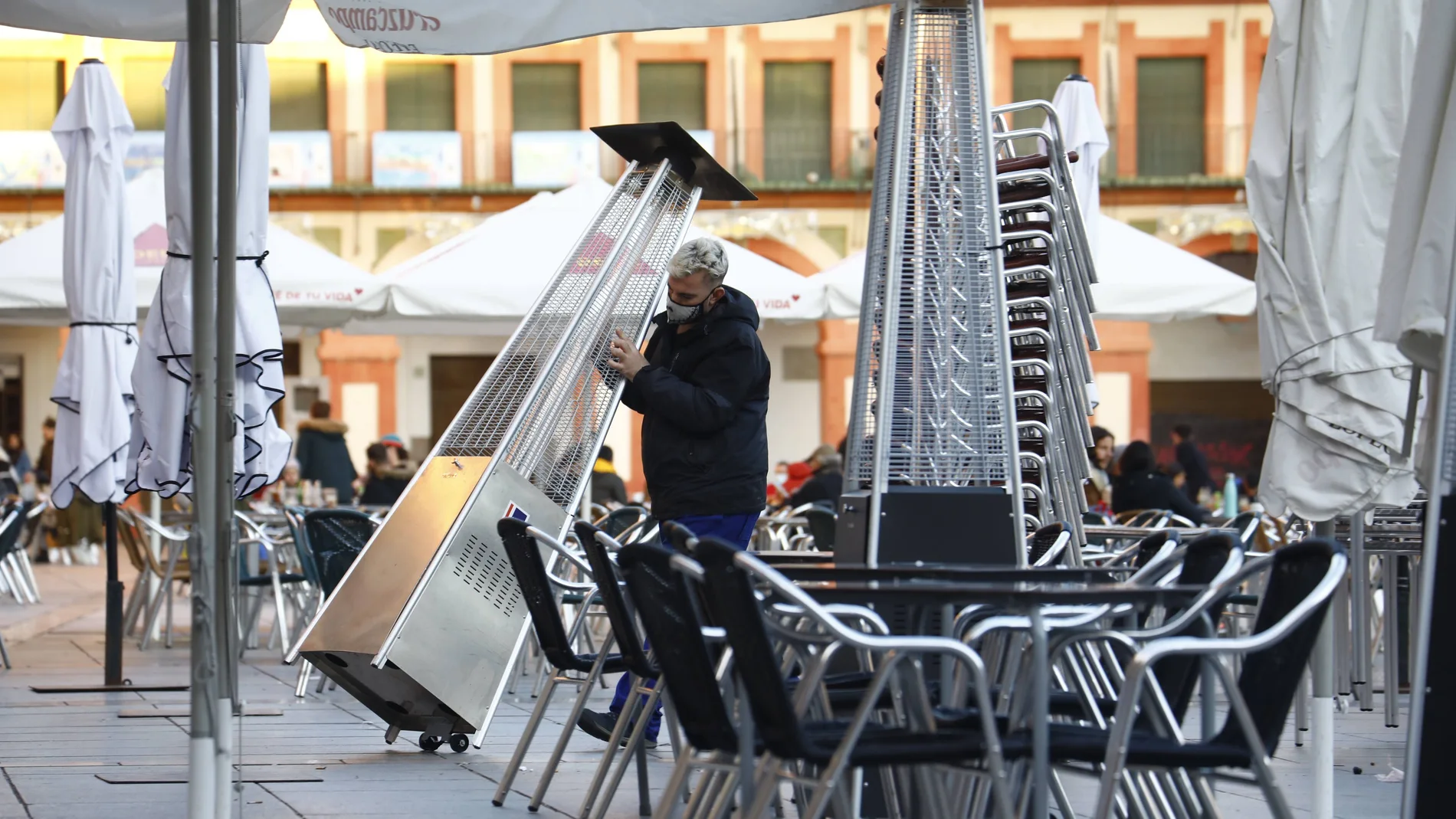 Imagen de archivo de un trabajador recoge el mobiliario de la terraza de un restaurante en el centro de Córdoba