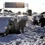 Máquinas quitanieves, efectivos de la Guardia Civil y de la UME trabajan en el km 58 de la M-40 en Madrid, para liberar de la nieve a varios coches