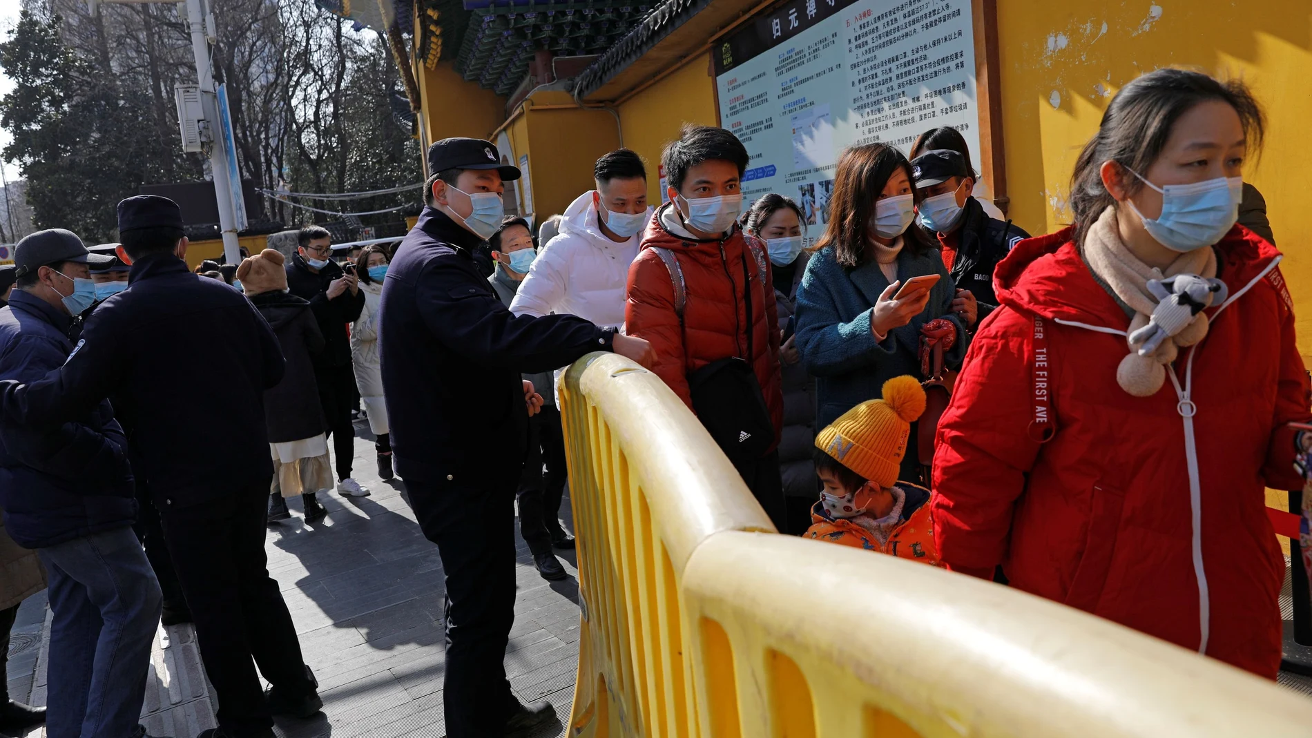 Police personnel guide the queue outside a Buddhist temple as people wearing protective face masks visit the temple on New Year?s Day, following the coronavirus disease (COVID-19) outbreak, in Wuhan, Hubei province, China January 1, 2021. REUTERS/Tingshu Wang
