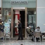 Un camarero atiende a unos clientes en la terraza de un bar de la calle Santa Teresa de Murcia