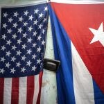 A U.S. and Cuban flags hang from a wall with an old photo camera hung in between in Havana, Cuba, Monday, Jan 11, 2021. The Trump administration has re-designated Cuba as a "state sponsor of terrorism" in a move that hits the country with new sanctions shortly before President-elect Joe Biden takes office. (AP Photo/Ramon Espinosa)