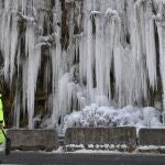 Un operario trabaja en una carretera frente a una pared congelada en el valle del Roncal (Navarra)