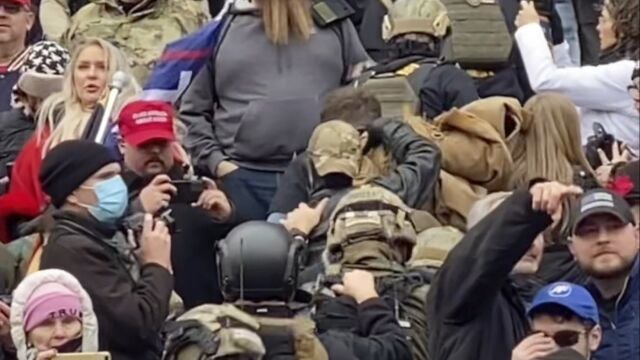 Una fila de hombres con cascos y chalecos antibalas de color verde oliva suben las escaleras de mármol del Capitolio de los EE. UU