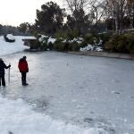 Personas caminan por un estanque helado en el Parque de San Isidro de Madrid, tras el paso del temporal Filomena