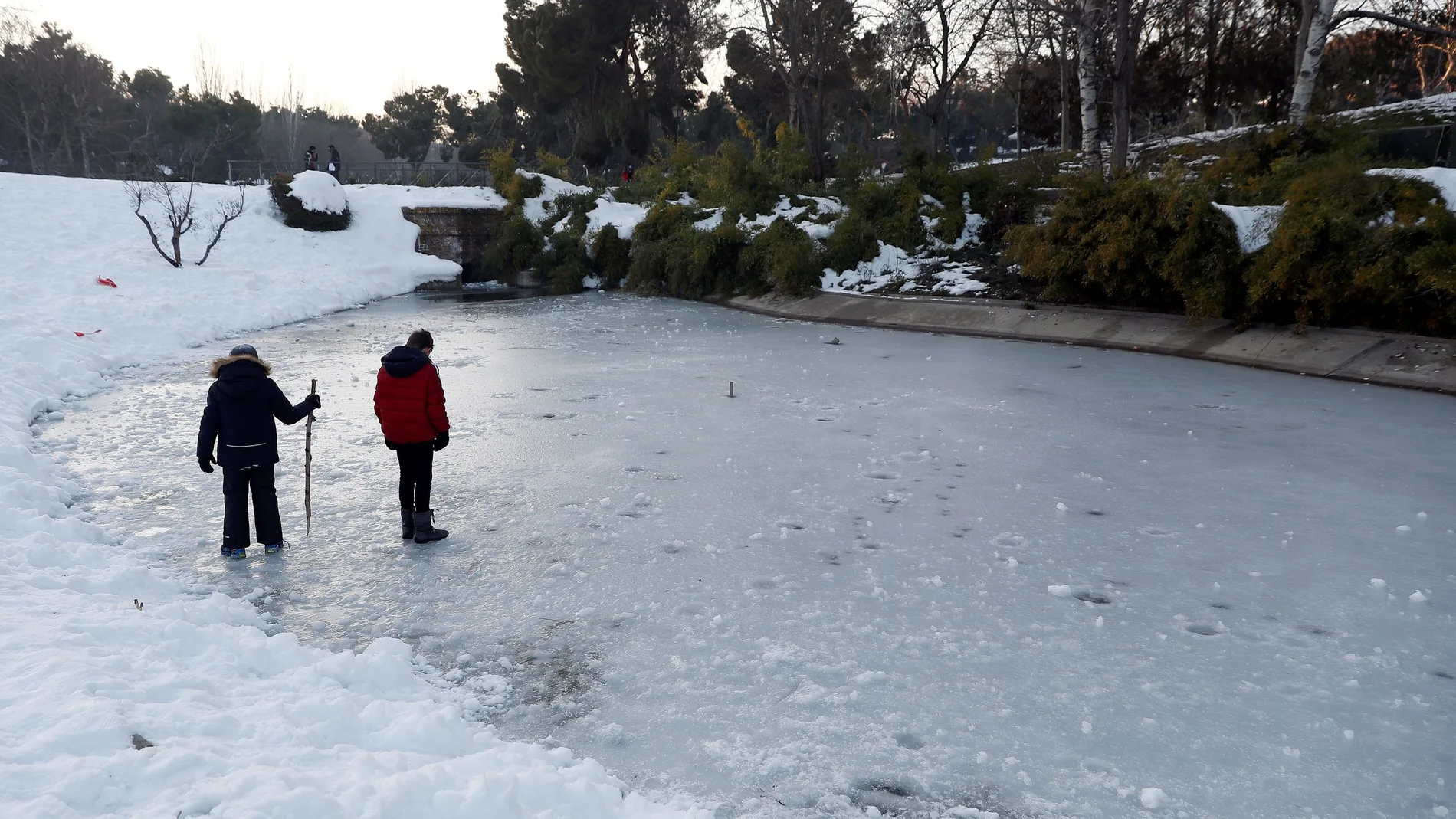 Personas caminan por un estanque helado en el Parque de San Isidro de Madrid, tras el paso del temporal Filomena