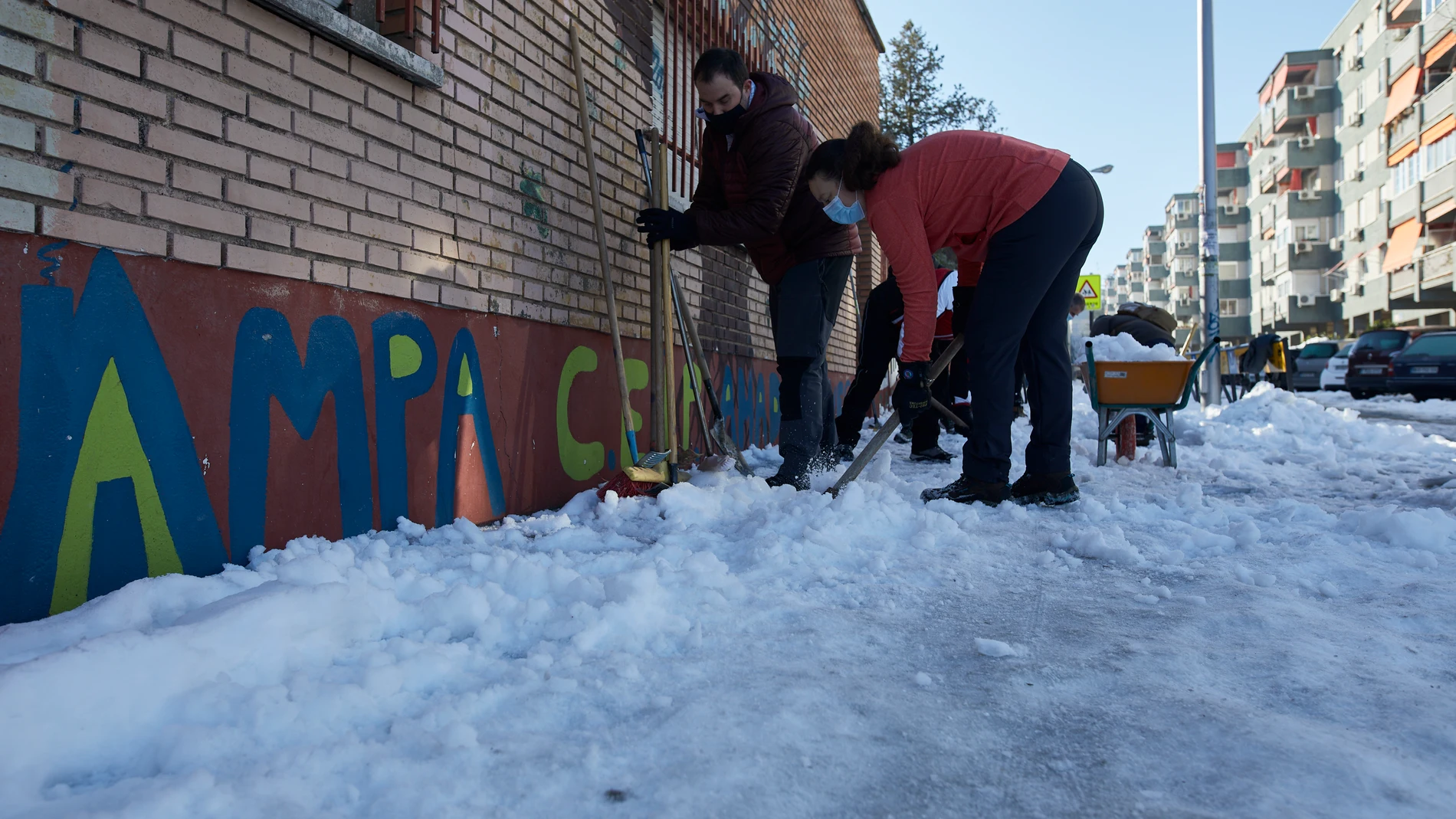 Varios familiares colaboran en la limpieza del hielo y la nieve en las inmediaciones del colegio Amadeo Vives tras la gran nevada