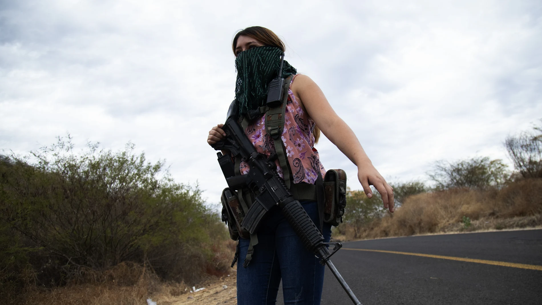 An armed woman who goes by the nickname "La Guera," and who says she is a member of a female-led, self-defense group, patrols the edge of her town El Terrero, where it shares a border with the town of Aguililla, in Michoacan state, Mexico, Thursday, Jan. 14, 2021. In other towns nearby, residents have dug trenches across roadways leading into neighboring Jalisco state, to keep attackers out. (AP Photo/Armando Solis)